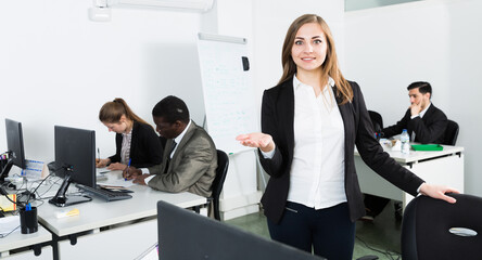 Wall Mural - Elegant young businesswoman politely welcoming to modern open plan office