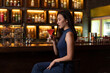 Nightlife concept a pretty girl with long hair wearing blue dress holding a pink drink appreciating the musics alone in the bar