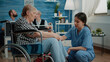 Old woman in nursing home receiving medical visit for checkup from nurse. Medical assistant doing consultation for patient with disability in wheelchair. Person with physical health issues