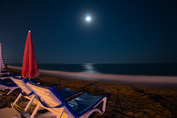 Wall Mural - Night beach, sand and sea views, umbrellas and sun loungers. Moon light. No body. coast and embankment Turkey Alanya. Copy space