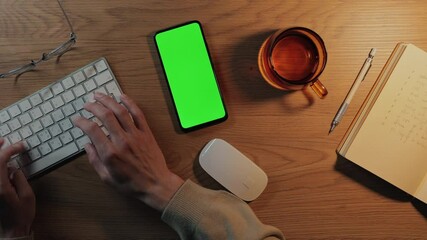 Close up of man using keyboard and green screen mobile