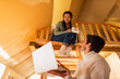 © LIGHTFIELD STUDIOS - Cheerful asian woman holding cups near blurred boyfriend with laptop in glamping house