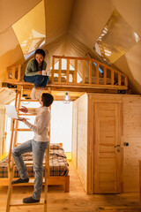 Wall Mural - Man pointing at laptop near asian girlfriend with cups in glamping house