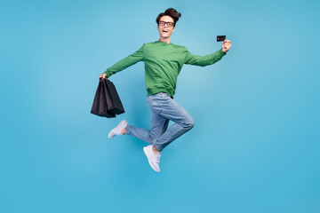 Full length body size photo guy jumping high showing credit card on shopping isolated pastel blue color background