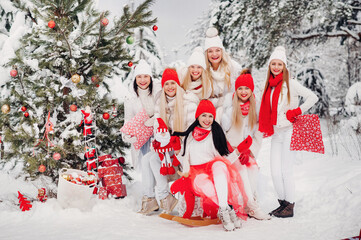 Wall Mural - A large group of girls with Christmas gifts in their hands standing in the winter forest.Girls in red and white clothes with Christmas gifts in the snowy forest