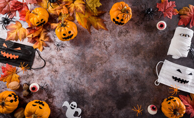 Wall Mural - Halloween decorations made from pumpkin, paper bats,medical mask and black spider on dark stone background. Flat lay, top view with copy space for text.