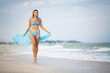 © YouraPechkin - A girl with blond hair in a bluish swimsuit and a bright shawl walks along the beach