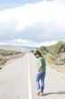 © javiemebravo - young man in hat walking down a deserted road turns to look