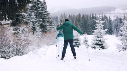 Wall Mural - Rear view of couple cross country skiing outdoors in winter nature, Tatra mountains Slovakia. Man almost having an accident.