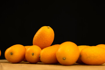 Wall Mural - Kumquat, fresh citrus fruits on a black backgroud. Cumquat, healthy food, raw diet concept. Copy space photo