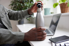 Close Up Of Thirsty Man In Office Opening Reusable Water Bottle For Drink