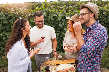 Happy friends having fun drinking wine at winery vineyard - Friendship concept with young people enjoying harvest time together