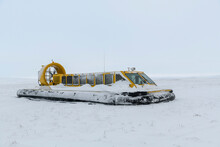 Hovercraft In Winter Tundra. Air Cushion On The Beach. Yellow Hover Craft Under Snow.
