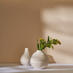 Sticker - Branch of goldenrod in a white ceramic vase against a beige wall