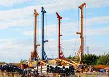 Multiple Piling Rigs Machines, In  The Storage Yard, After Service And Repair, Awaiting To Be Dispatched To Construction Site For Deep Foundation Piling Works, Against Blue Sky Background 