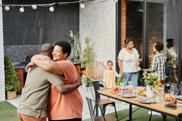 Canvas Print - Portrait of mature African-American woman embracing friend during family gathering at dinner party outdoors, copy space