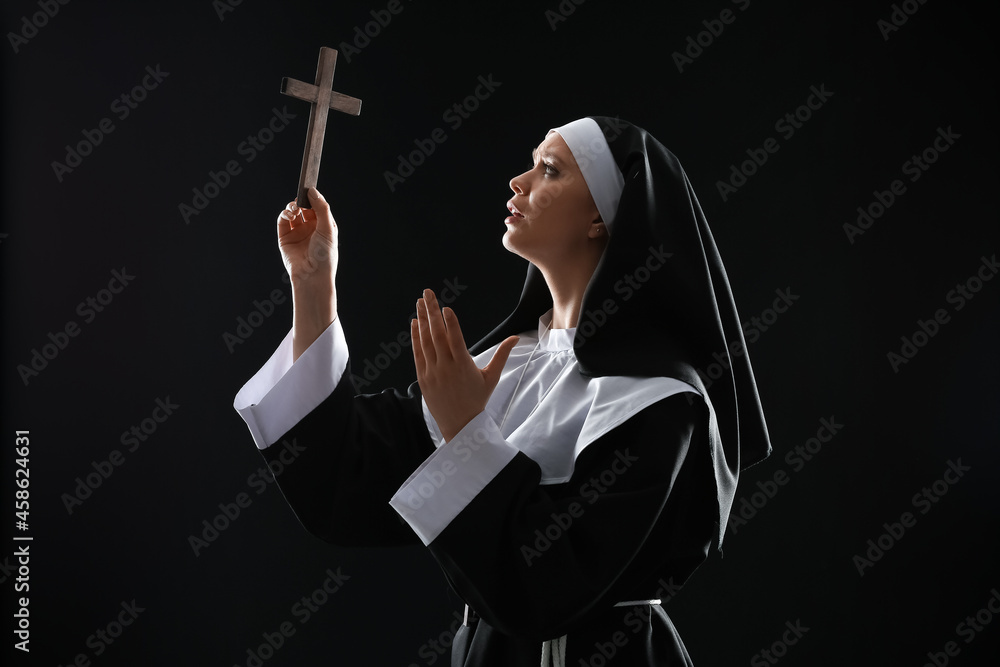 Young nun with cross on dark background