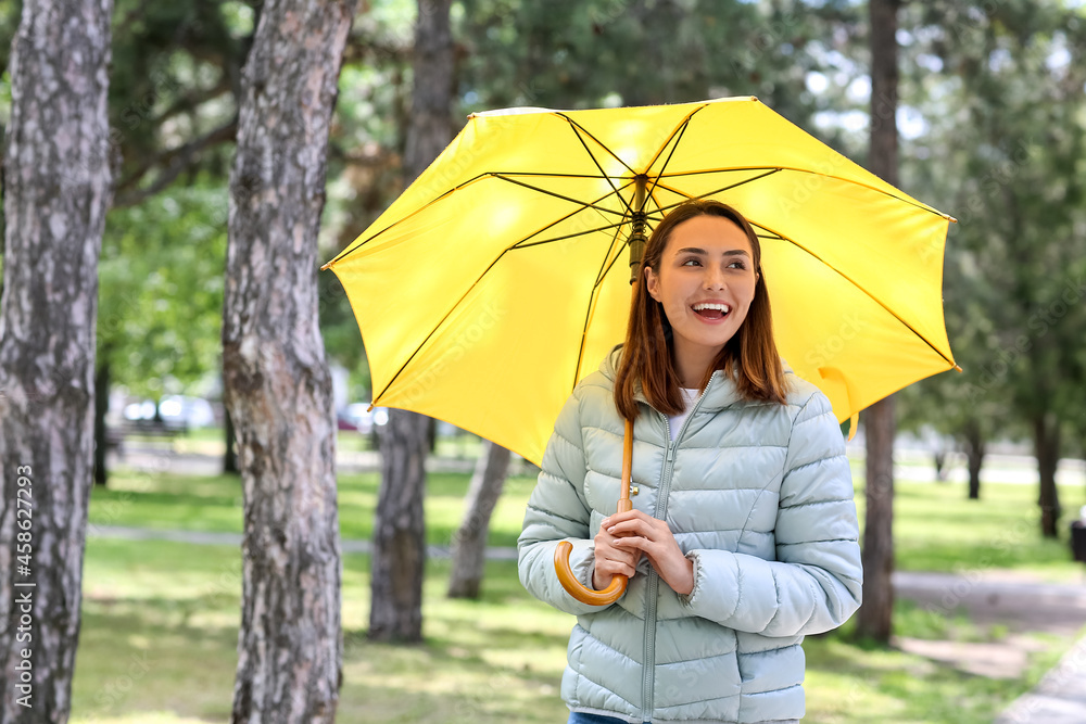 Beautiful young woman with umbrella in park