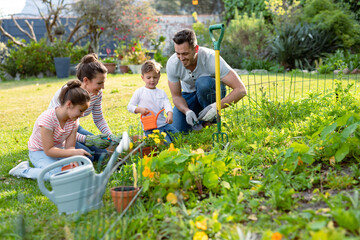 Happy caucasian family gardening and watering plants together