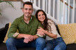 © WavebreakMediaMicro - Happy caucasian couple sitting on sofa and looking at camera