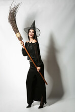 Young Witch With Broom On Light Background