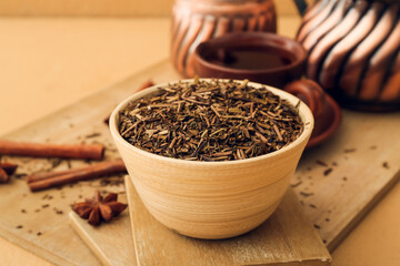 Poster - Board with dry hojicha green tea and cup of hot beverage on color background