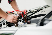 Close Up Of Automotive Mechanics Using Jump Leads For Jump Starting Automotive Batteries When Suffering From A Discharged Battery In The Garage, Checking And Maintenance Service Concept.