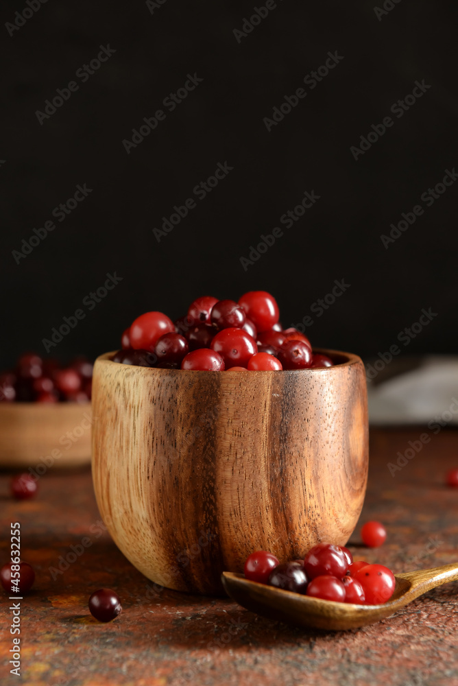 Bowl with healthy cranberries on grunge background