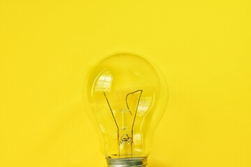 Broken incandescent light bulb on yellow background