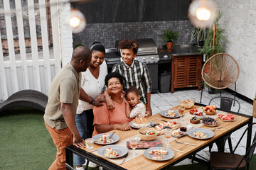 Portrait of big African-American family celebrating loving grandmother at dinner outdoors, copy space