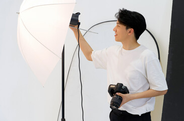 Wall Mural - Asian photographers are adjusting the brightness of lights for shooting fashion models in the studio.