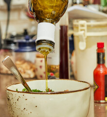 Wall Mural - Cook pours oil into salad in deep bowl