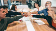 © Jacob Lund - Cheerful businesspeople bringing their fists together in a boardroom