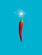 © Aleksandar - Single red hot chili pepper with fire sparkler isolated on a vibrant blue background. Creative spicy vegetable food concept. New Year or Christmas party decoration. Fashion minimal art.