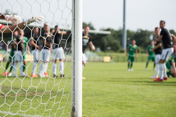 Wall Mural - Detail of goal's post with net and football players during free kick in the background.