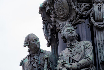 a fragment of a stone sculpture depicting two men in antique camisoles and wigs with haughty faces looking into the distance