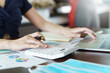 © nopparat - Businesswoman working from home with a calculator and financial report on wooden table.