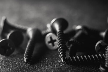 Wall Mural - Grayscale shot of a pile of bolts and nuts on a dark blurred background