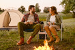 © Drobot Dean - White couple smiling and drinking tea during camping together