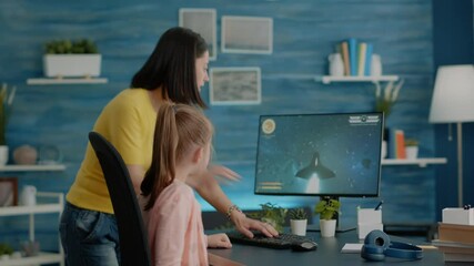 Wall Mural - Young girl playing video games on computer while mom interrupting fun activity after online school. Child enjoying action shooting game and mother turning off monitor and play at home.