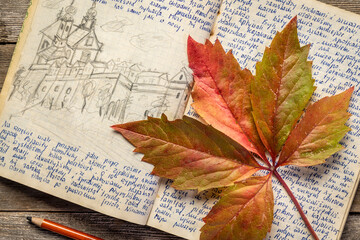 Wall Mural - Vintage expedition journal on a rustic picnic table with a colorful leaf. Travel log from paddling trip across Poland in 1974 - handwriting and drawing in pencil. Copyright by the photographer.