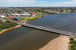 © Austockphoto - Arial view of a bridge over a wide brown river with a town on one side and a beach on the other
