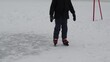 cute preschooler or teenager boy learn to skate on ice rink. Kid wearing winter jacket, red hat and neckwarmer standing on one knee. walk in the fresh air