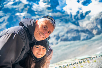 Canvas Print - Happy young girl hugging hel father on a mountain excursion trail.