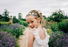 Young Flower Girl Smiling At A Wedding In A Beautiful Field Of Flowers
