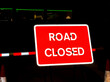 Highly reflective road closed sign at night in a city centre. No people.