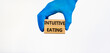 Intuitive eating symbol. Doctor hand in blue glove holds wooden blocks with words Intuitive eating, beautiful white background. Medical and intuitive eating concept.