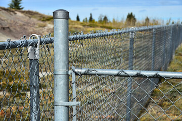 A close up image of a metal chain link fence enclosure in a public park.  