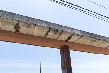 Wall Mural - Elevated street, concrete sections atop an orange central support, dark metal upright support and electrical lines against blue sky, horizontal aspect