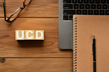 On the table there is a word cube lined UCD with laptop computers and glasses. It is an abbreviation for the word User-Centered Design.